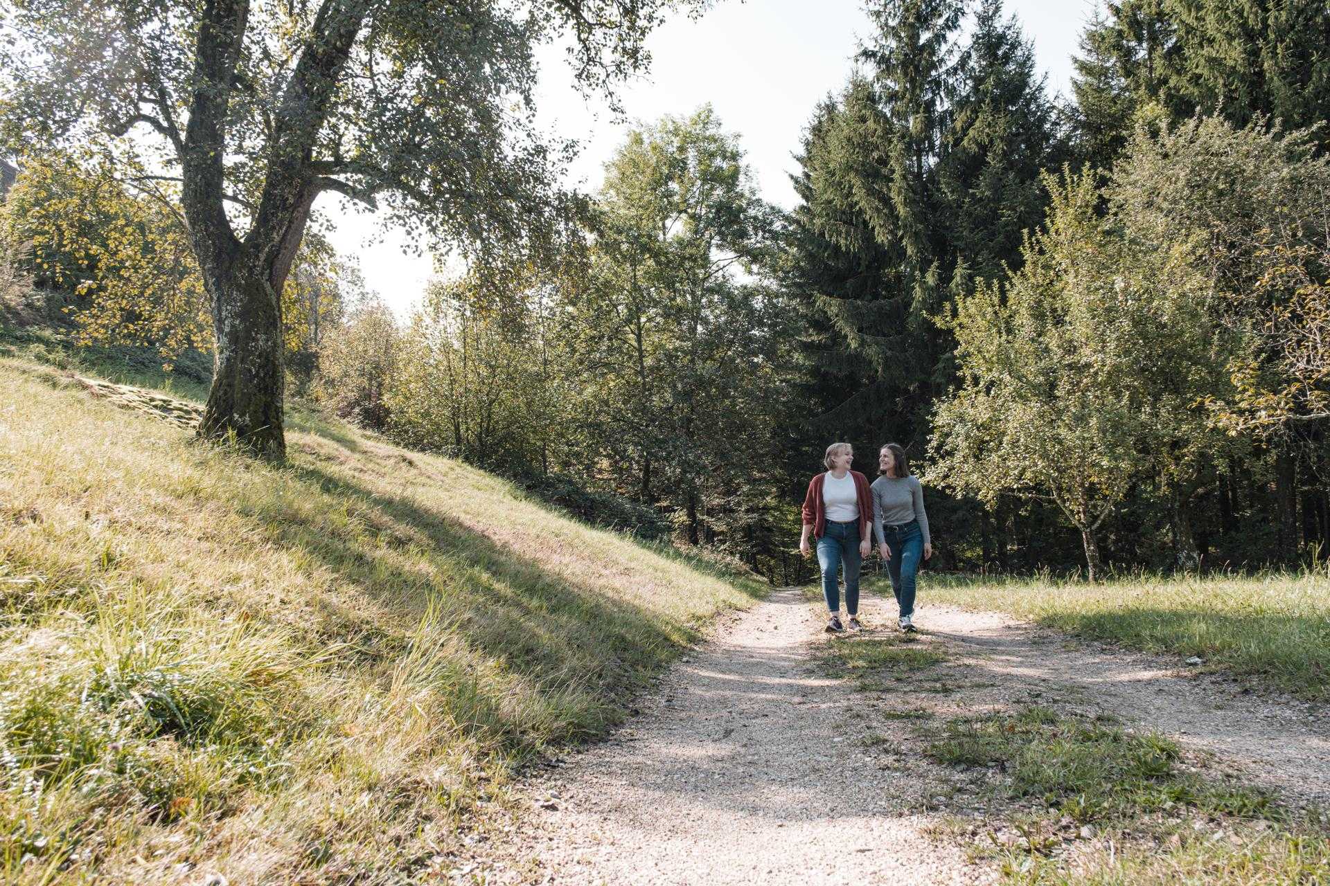 Maya und Sarah gehen gemeinsam auf einem Waldweg